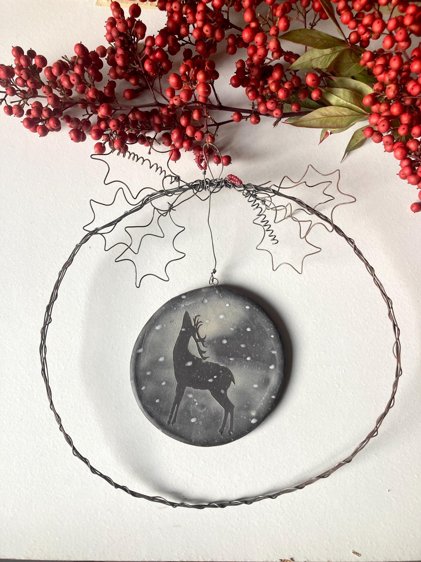Ghirlanda in filo di ferro con medaglione in gres nero decorato con paesaggio innevato