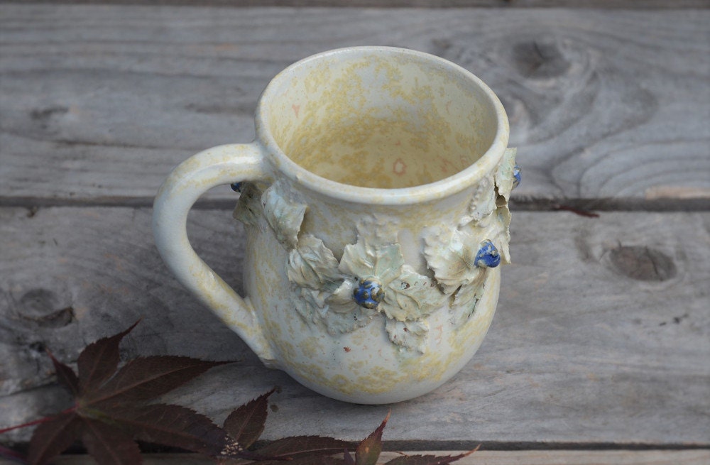 Tazza in gres color crema con uccellino sul manico e rami di more, fatta a mano al tornio