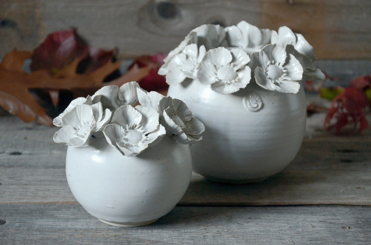 Vaso sferico bianco in gres con una corolla di fiori di dalia sulla sommità