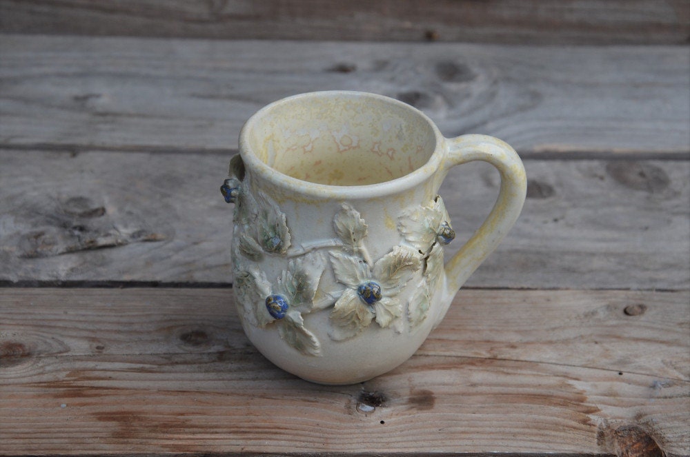 Tazza in gres color crema con uccellino sul manico e rami di more, fatta a mano al tornio