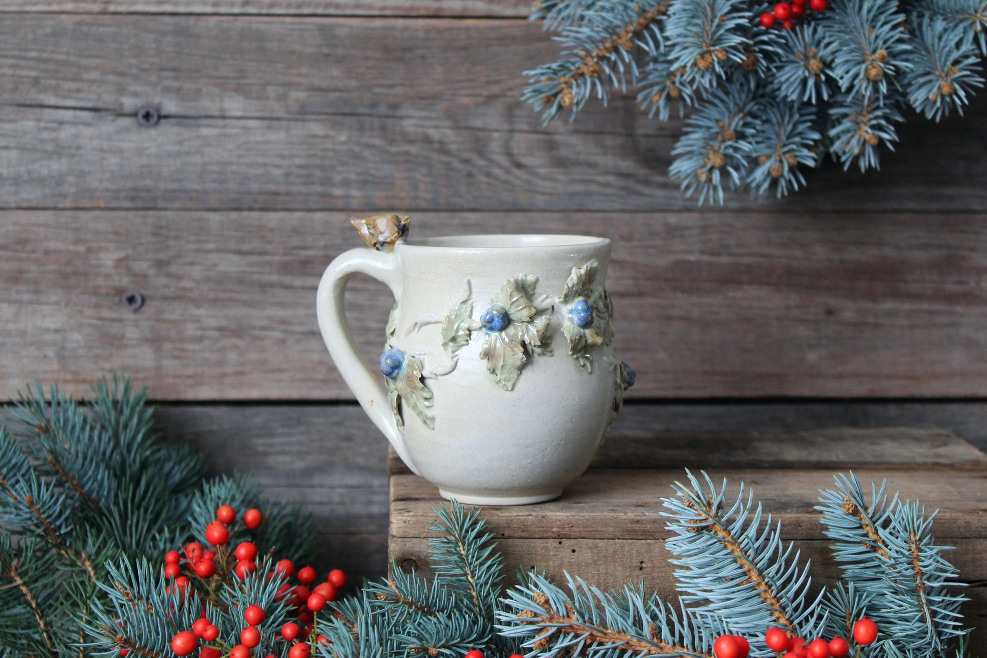 Tazza in gres color crema con uccellino sul manico e rami di more, fatta a mano al tornio