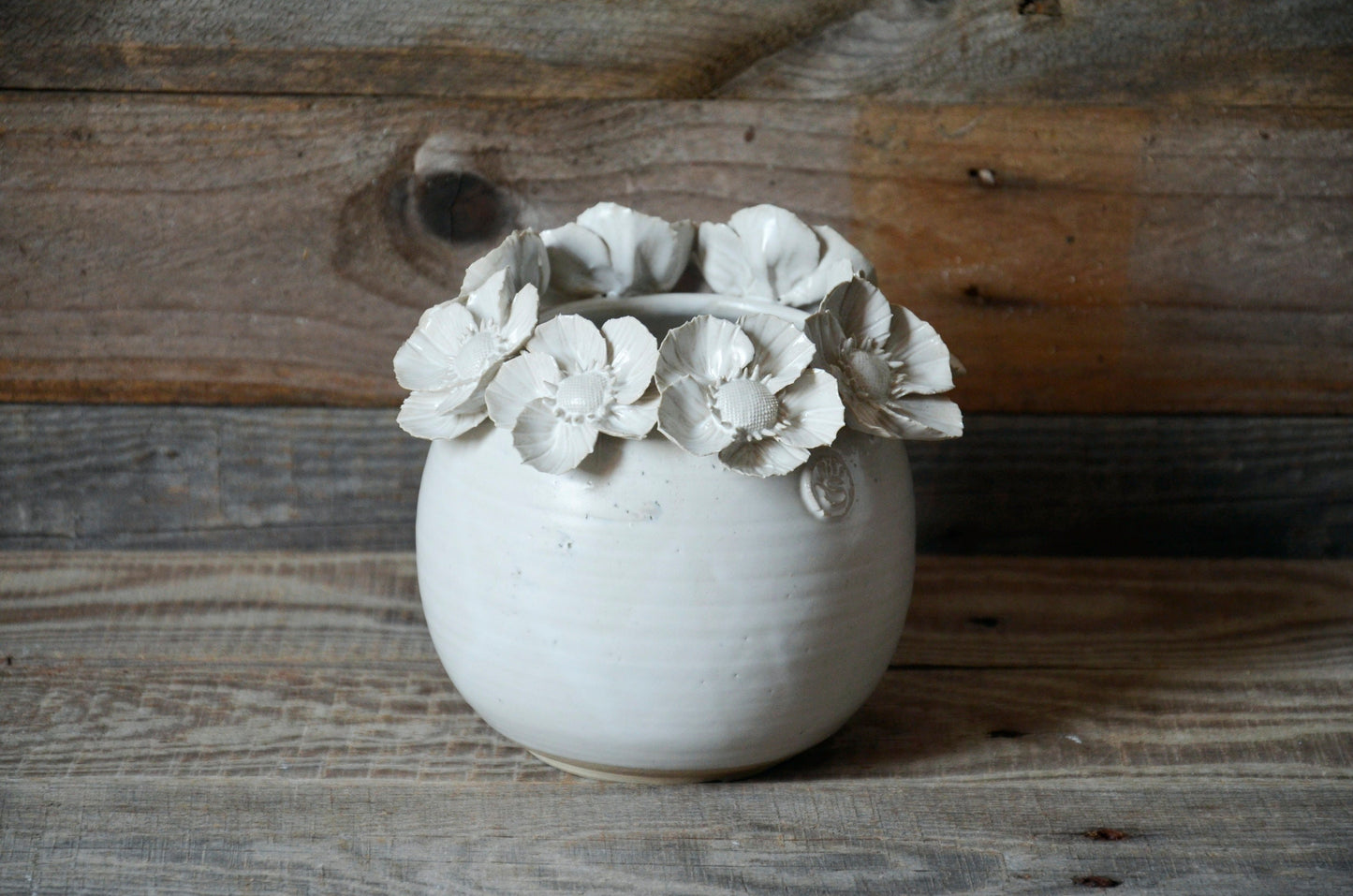 Vaso sferico bianco in gres con una corolla di fiori di dalia sulla sommità